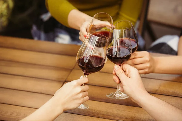 Gente tintineando vasos con vino en la terraza de verano de la cafetería o restaurante. Primer plano, estilo de vida . — Foto de Stock