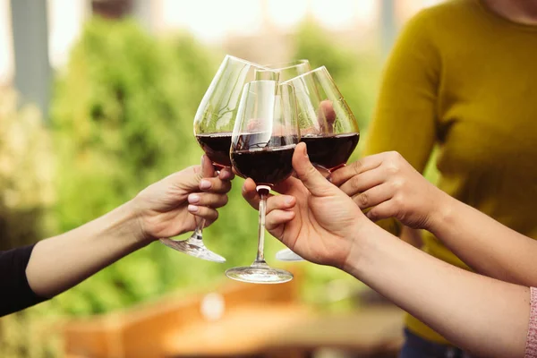 Gente tintineando vasos con vino en la terraza de verano de la cafetería o restaurante. Primer plano, estilo de vida . — Foto de Stock