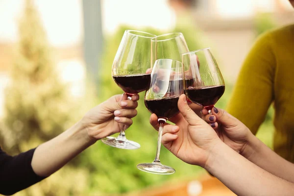 Gente tintineando vasos con vino en la terraza de verano de la cafetería o restaurante. Primer plano, estilo de vida . — Foto de Stock