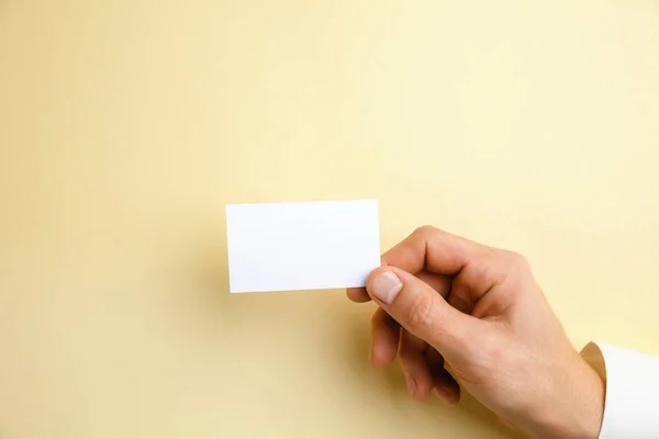 Férfi kéz kezében egy üres névjegykártya lágy sárga háttér szöveg vagy design — Stock Fotó