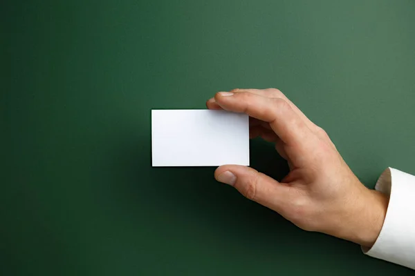 Férfi kéz kezében egy üres névjegykártya zöld alapon szöveg vagy design — Stock Fotó