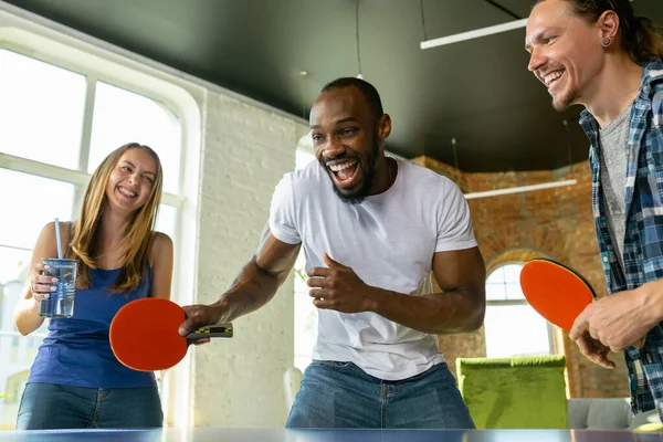 Jóvenes jugando al tenis de mesa en el lugar de trabajo, divirtiéndose — Foto de Stock