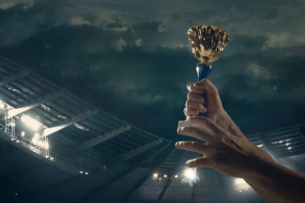 勝利の賞、曇った暗い空に対して勝者のカップを締め男性の手 — ストック写真