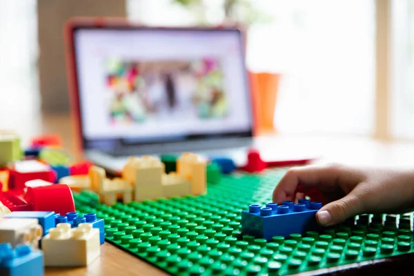 Flicka leker med konstruktören hemma, tittar på lärare handledning på laptop. Digitalisering, distansutbildning — Stockfoto