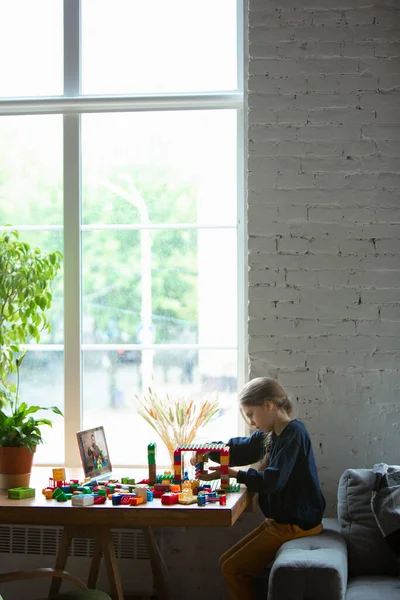 Chica jugando con el constructor en casa, viendo profesores tutorial en el ordenador portátil. Digitalización, educación a distancia — Foto de Stock