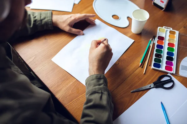 Primer plano del dibujo del hombre con pinturas y lápices en casa. Educación remota, ocupación creativa, terapia de arte — Foto de Stock