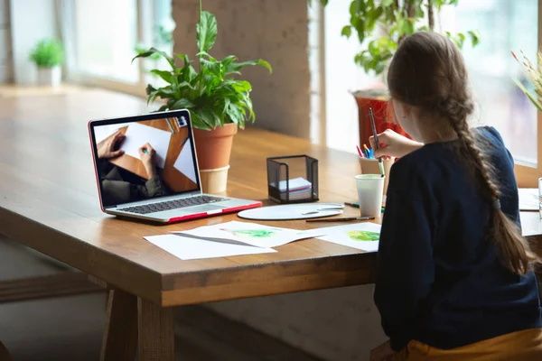 Meisje tekening met verf en potloden thuis, kijken naar docenten tutorial op laptop. Digitalisering, onderwijs op afstand — Stockfoto