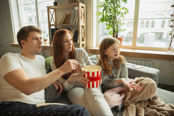 Family spending nice time together at home, looks happy and cheerful, watching TV