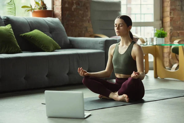 Спортивна молода жінка бере уроки йоги онлайн і практикує вдома — стокове фото