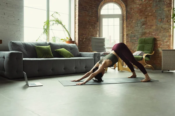 Giovane donna sportiva che prende lezioni di yoga online e pratica a casa — Foto Stock