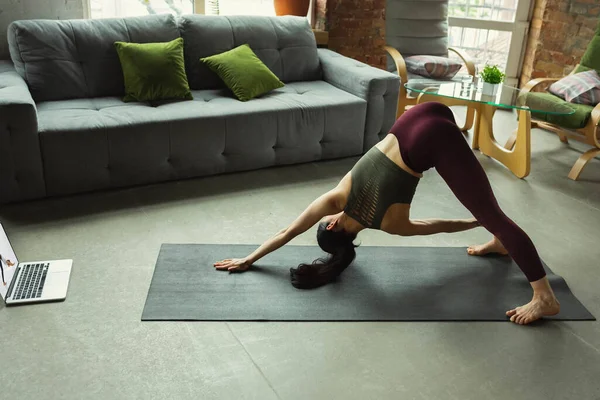 Sportliche junge Frau nimmt Yoga-Unterricht online und übt zu Hause — Stockfoto
