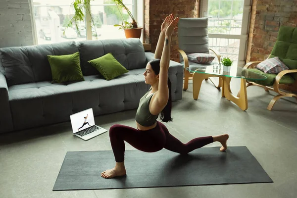 Sportieve jonge vrouw die online yoga lessen neemt en thuis oefent — Stockfoto