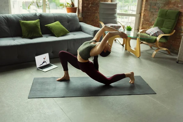 Giovane donna sportiva che prende lezioni di yoga online e pratica a casa — Foto Stock