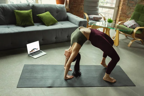 Giovane donna sportiva che prende lezioni di yoga online e pratica a casa — Foto Stock
