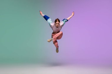 Neon ışıklarıyla dans eden, dans salonunun arka planında şık giysiler içinde hip-hop yapan kız..
