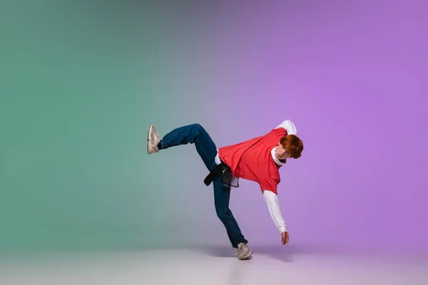 Boy dancing hip-hop in stylish clothes on gradient background at dance hall in neon light. — Stock Photo, Image