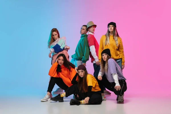 Groep dansers, jongens en meisjes dansen hip-hop in stijlvolle kleding op gradiënt studio achtergrond in neon licht. — Stockfoto