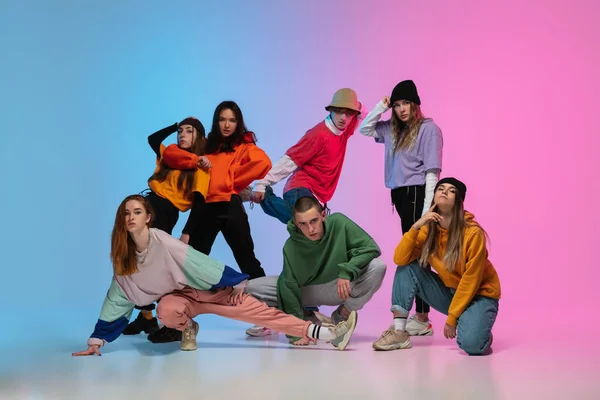 Grupo de bailarines, niños y niñas bailando hip-hop con ropa elegante sobre fondo de estudio degradado en luz de neón . — Foto de Stock