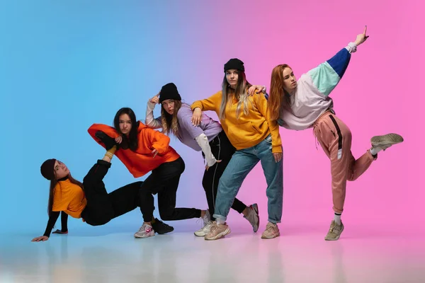 Groep dansers, jongens en meisjes dansen hip-hop in stijlvolle kleding op gradiënt studio achtergrond in neon licht. — Stockfoto