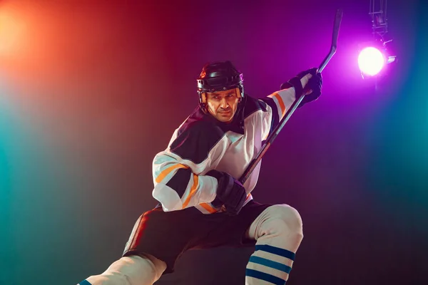 Férfi hoki játékos a bottal a jégpályán és sötét neon színű háttér — Stock Fotó