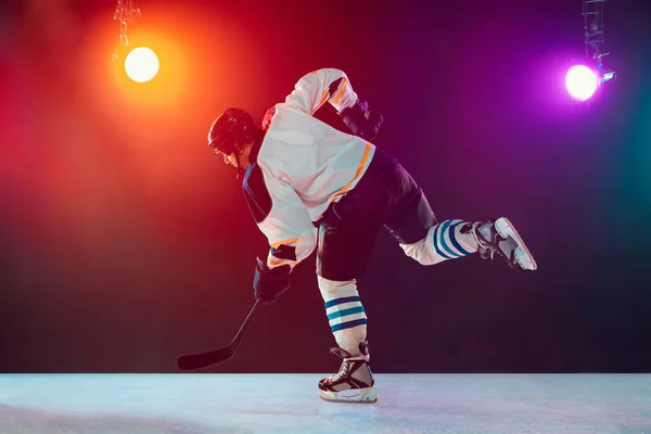 Чоловічий хокеїст з палицею на крижаному дворі і темно-неоновим кольоровим фоном — стокове фото
