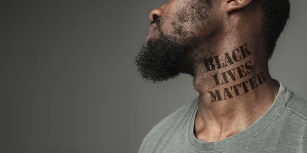 Ritratto ravvicinato di un uomo di colore stanco della discriminazione razziale ha tatuato slogan sul collo — Foto Stock