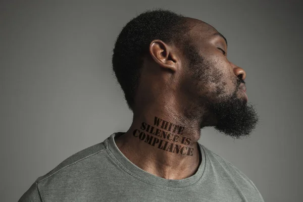인종 차별에 지친 흑인의 초상을 클로즈업하는 것은 그 의 목에 구호를 문신했다. — 스톡 사진