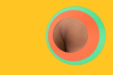 Body of african-american man peeking throught circle in yellow background clipart