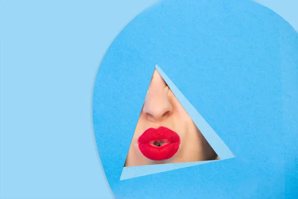 Женские красные губы, смотрящие сквозь треугольник на синем фоне — стоковое фото