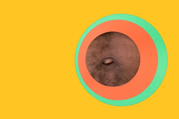 Тело афро-американского мужчины, заглядывающего сквозь круги на желтом фоне — стоковое фото