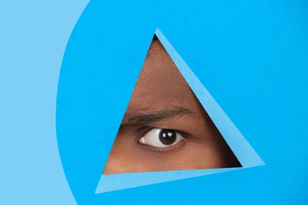 아프리카 계 미국인의 눈파란 배경에 삼각형을 보고 있는 남자 — 스톡 사진