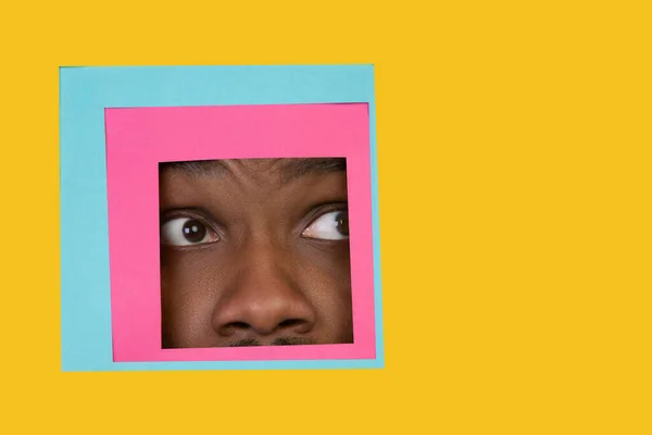 Cara del hombre afroamericano mirando a través de la plaza en el fondo amarillo — Foto de Stock