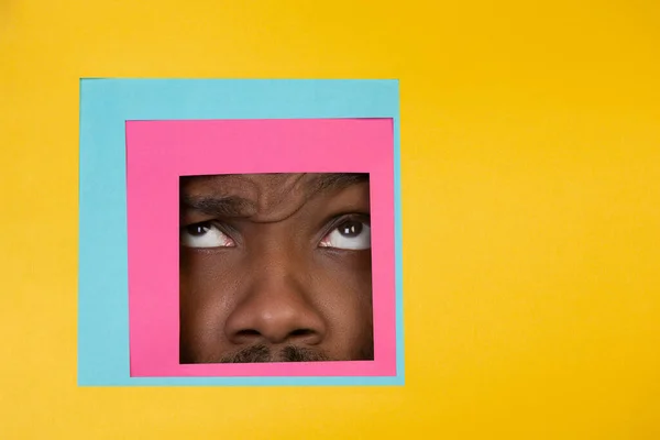 흑인 남자가 노란 배경에서 사각형을 보고 있는 얼굴 — 스톡 사진