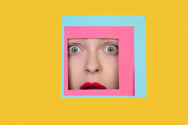 Лицо кавказки, смотрящей сквозь квадрат на желтом фоне — стоковое фото