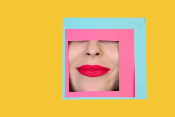 Rosto de mulher caucasiana espreitando através de quadrado em fundo amarelo — Fotografia de Stock