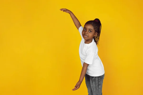 Little african-american girls portrait isolated on yellow studio background — Stok Foto