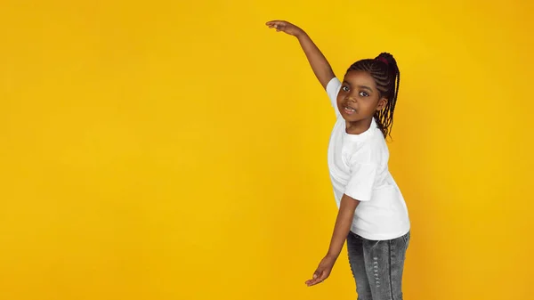 Little african-american girls portrait isolated on yellow studio background — Stok Foto