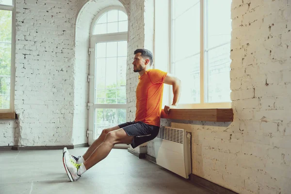 Junge kaukasische Mann Training zu Hause während der Quarantäne von Coronavirus Ausbruch, Übungen der Fitness, Aerobic. Während der Isolierung sportlich bleiben. — Stockfoto