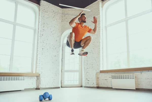 Молодий кавказький чоловік тренується вдома під час карантину спалаху коронавірусу, виконує вправи з фізичної підготовки, аеробні. Спортивний відпочинок під час утеплення . — стокове фото