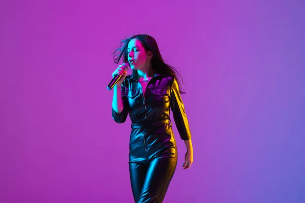 Kaukázusi női énekes portré elszigetelt lila stúdió háttér neon fény — Stock Fotó