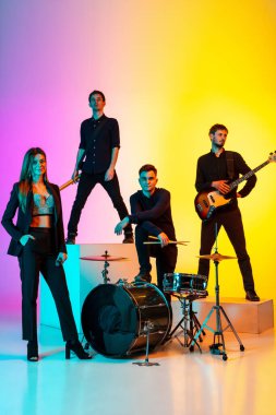 Genç Kafkasyalı müzisyenler, müzik grubu gradient stüdyo arka planında neon ışığı altında performans sergiliyor.