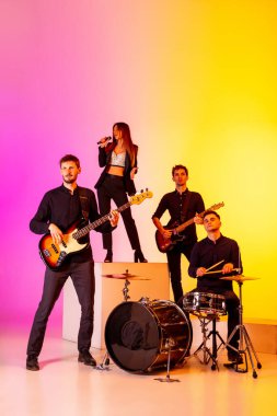 Genç Kafkasyalı müzisyenler, müzik grubu gradient stüdyo arka planında neon ışığı altında performans sergiliyor.