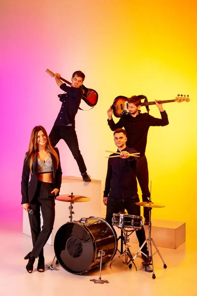 Junge kaukasische Musiker, Band, die im Neonlicht auf dem Hintergrund des Gradienten-Studios auftritt — Stockfoto
