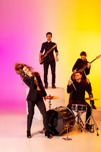 Junge kaukasische Musiker, Band, die im Neonlicht auf dem Hintergrund des Gradienten-Studios auftritt — Stockfoto