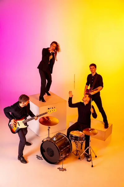 Jóvenes músicos caucásicos, banda actuando en luz de neón en el fondo del estudio gradiente — Foto de Stock