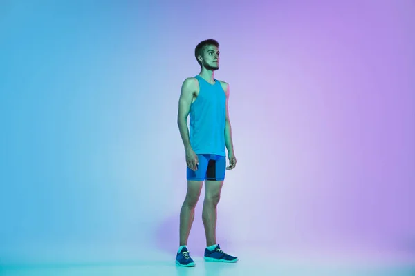 Full length portrait of active young caucasian running, jogging man op gradiënt studio achtergrond in neon licht — Stockfoto