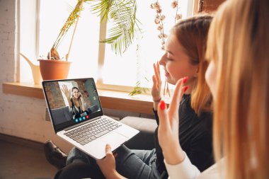 Kadınlar sanal toplantı sırasında dizüstü bilgisayara bakarak video konferansına katılıyor, iş için video kamera uygulaması kullanıyor, kapatıyor
