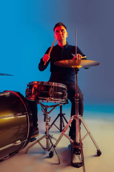 Tambor masculino caucásico improvisando aislado sobre fondo de estudio azul en luz de neón — Foto de Stock