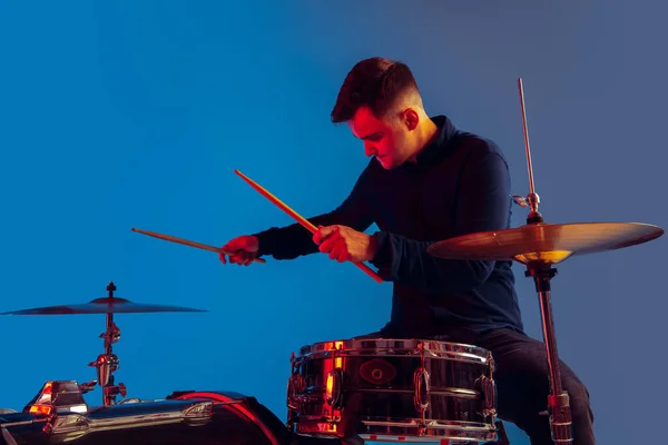 Vit manlig trummis improvisation isolerad på blå studio bakgrund i neon ljus — Stockfoto