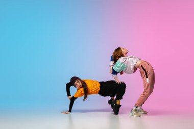 Neon ışıklı dans salonunda, arka planda hip-hop dansı yapan kızlar..